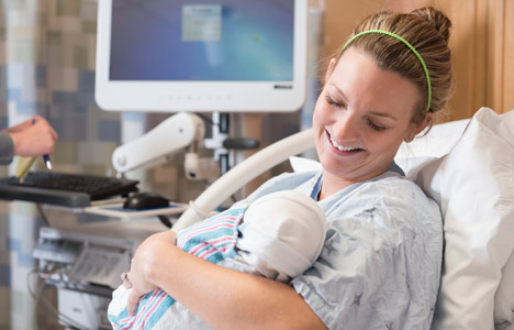 Patient smiling down at newborn baby